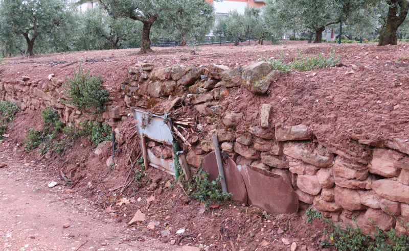 Muro de contención de piedra por gravedad, entrelazado con chapas y otros materiales